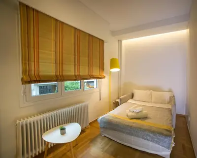 a bedroom with a bed and a table and a window at Skoufa Apartment in Athens