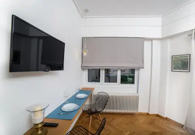 a living room with a table and a flat screen tv at Skoufa Apartment in Athens