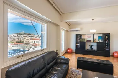 a living room with a leather couch and a large window at ATHENStay Penthouse Suite in Athens