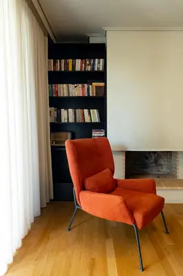 an orange chair in a living room with a fireplace at Elliniko Luxury Residence by First Class Properties in Athens
