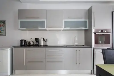 a kitchen with white cabinets and stainless steel appliances at Glyfada Riviera Home in Athens