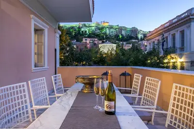 a table with two wine bottles and glasses on a balcony at Aerides 3 Luxury Suites in Athens