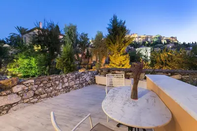 a table and chairs on a patio with a stone wall at Aerides 3 Luxury Suites in Athens