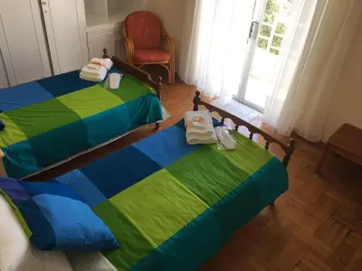 a bedroom with two beds and a chair and a window at Apartment in Markopoulo center in Markopoulo