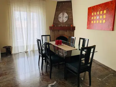 a dining room with a table and chairs and a clock at Apartment in Markopoulo center in Markopoulo