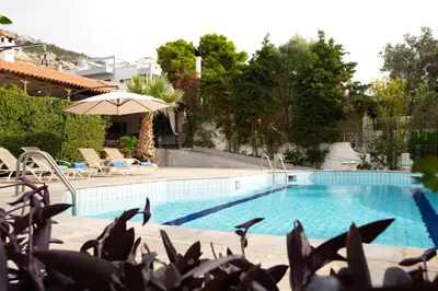 a swimming pool with chairs and an umbrella at Casa Saronida in Lagonissi