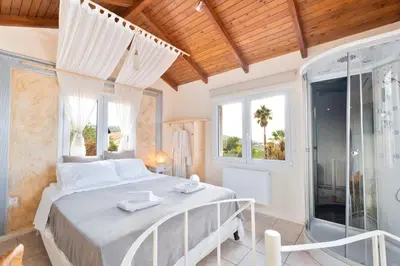 a bedroom with a king sized bed and a shower at Casa Saronida in Lagonissi