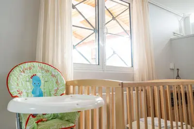 a crib and a chair in a room with a window at Casa Saronida in Lagonissi