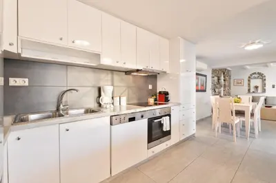 a kitchen with white cabinets and a sink and a table at Casa Saronida in Lagonissi