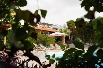a swimming pool with chairs and an umbrella at Casa Saronida in Lagonissi