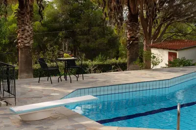 a swimming pool with a table and chairs next to a house at Casa Saronida in Lagonissi