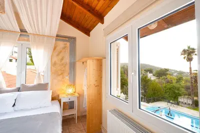 a bedroom with a bed and a large window at Casa Saronida in Lagonissi