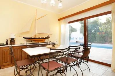 a dining room with a table and a sailboat on the wall at Villa Soula in Anavissos