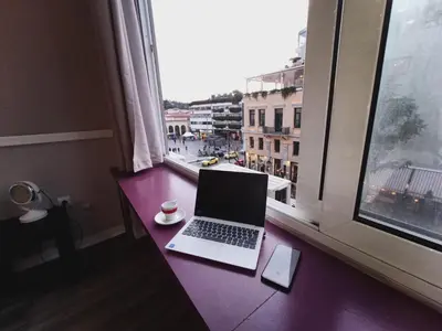 a laptop computer sitting on a purple desk next to a window at Ermou & Athinas Suites in Monastiraki in Athens
