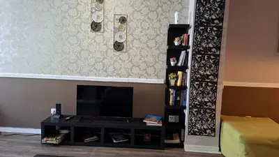 a living room with a television and a book shelf at Ermou & Athinas Suites in Monastiraki in Athens