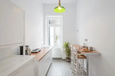 a white kitchen with a table and a stool at Athens Residence Apartments in Athens