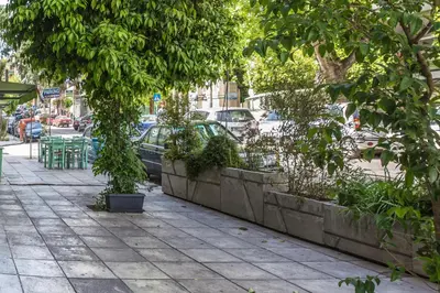 a sidewalk with trees and a car on a street at The Athens Insider in Athens