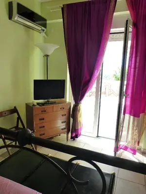 a bedroom with a bed and a tv and a window at Seaview near Athens & Sounio in Anavissos