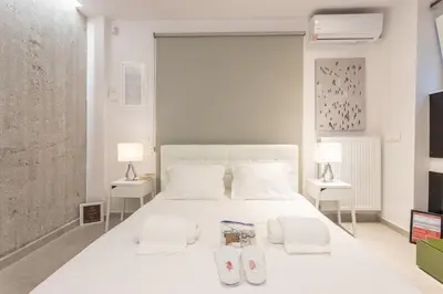 a white bedroom with a large white bed with two lamps at Stadium HiEnd Studio Top Location in Athens