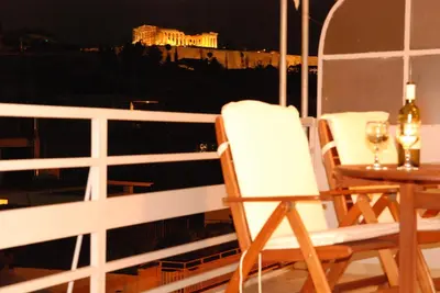a balcony with two chairs and a table with wine glasses at Acropolis View Luxury Suite in Athens