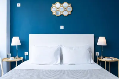 a blue bedroom with a white bed and two lamps at Enattica Syntagma Living in Athens