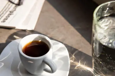 a cup of coffee on a white plate on a table at Enattica Syntagma Living in Athens