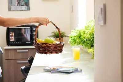 a person holding a basket of fruit on a table with a drink at Enattica Syntagma Living in Athens