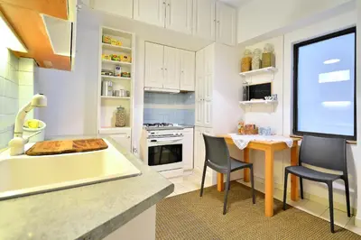 a kitchen with white cabinets and a table and chairs at Plaka Elegant Apartment in Athens