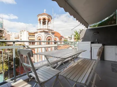 a table and chairs on a balcony with a church at Acropolis Charming Apartment with Large Balcony - DM17 in Athens