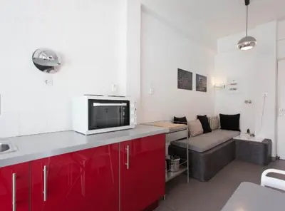 a kitchen with red cabinets and a couch in a room at Acropolis Charming Apartment with Large Balcony - DM17 in Athens