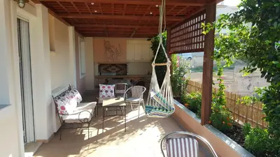 a porch with a hammock and chairs on a patio at House,1000m from beach in Lagonissi