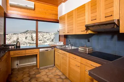 a kitchen with wooden cabinets and a view of a city at Exclusive Spacious Apartment with Expansive City Views - ST8 in Athens