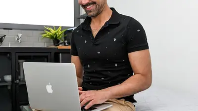 a man is smiling while holding a laptop computer at Monastiraki CityCenter Sleepbox- Unspoiled Athens Apartments in Athens