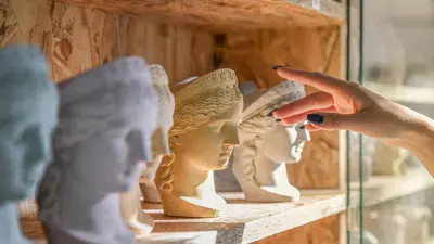 a woman points to a figurine of a head at Monastiraki CityCenter Sleepbox- Unspoiled Athens Apartments in Athens