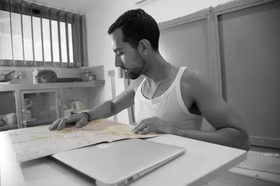 a man sitting at a table looking at a map at Monastiraki CityCenter Sleepbox- Unspoiled Athens Apartments in Athens