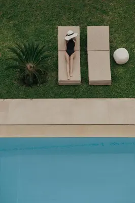 a woman in a hat sitting on a bench next to a pool at Golden Sun Hotel in Athens