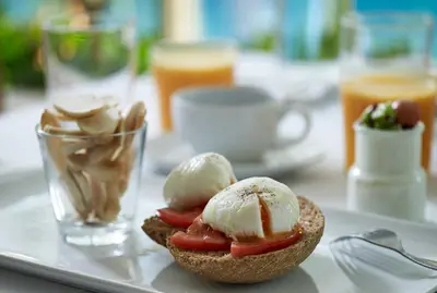 a piece of bread with ice cream and tomatoes on a tray at Golden Sun Hotel in Athens