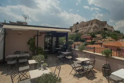 a patio with tables and chairs and a mountain at Hotel Byron in Athens