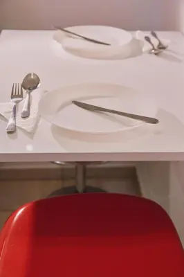 a white table with a red chair and plates and silverware at Modern and Cozy Apartment in the centre of Athens in Athens