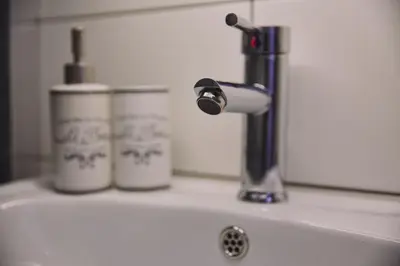a bathroom sink with a faucet and two cups on it at Modern and Cozy Apartment in the centre of Athens in Athens