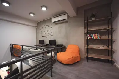 a room with an orange chair and a desk at Bedbox Hostel in Athens