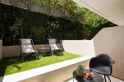 two chairs and a table on a patio with grass at Athenian Riviera Hotel& Suites in Athens
