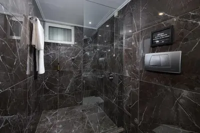 a bathroom with a shower with black marble tiles at Athenian Riviera Hotel& Suites in Athens