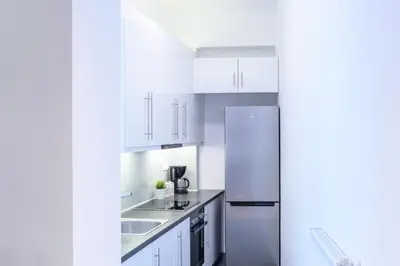 a white kitchen with white cabinets and a refrigerator at Modern design apartment near Acropolis in Athens