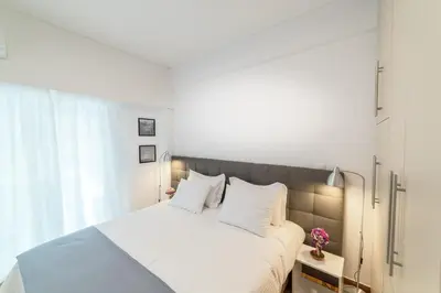 a bedroom with a bed with white sheets and a window at Modern design apartment near Acropolis in Athens