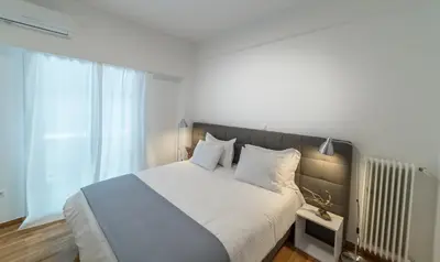 a bedroom with a white bed with a large window at Modern design apartment near Acropolis in Athens