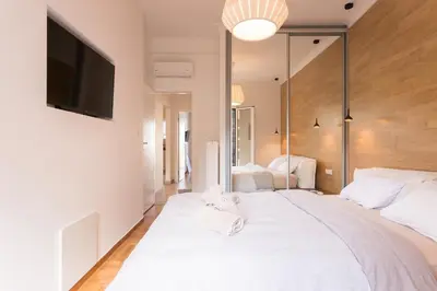a bedroom with a large white bed with a flat screen tv at Pagrati 2bdr Flat in Athens