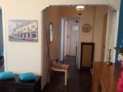 a living room with a table and a clock on the wall at Superb Athenian Nest in Athens
