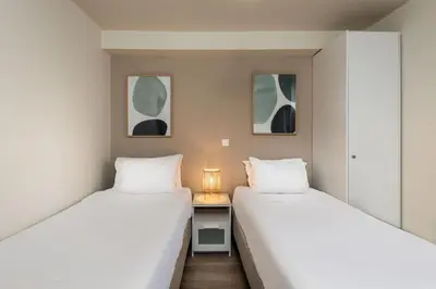 two beds in a room with a desk and two windows at Vouliagmeni Stylish Homes by BluPine in Athens