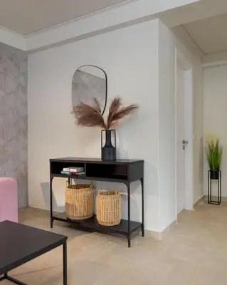 a black console table with a mirror and two baskets at Vouliagmeni Stylish Homes by BluPine in Athens